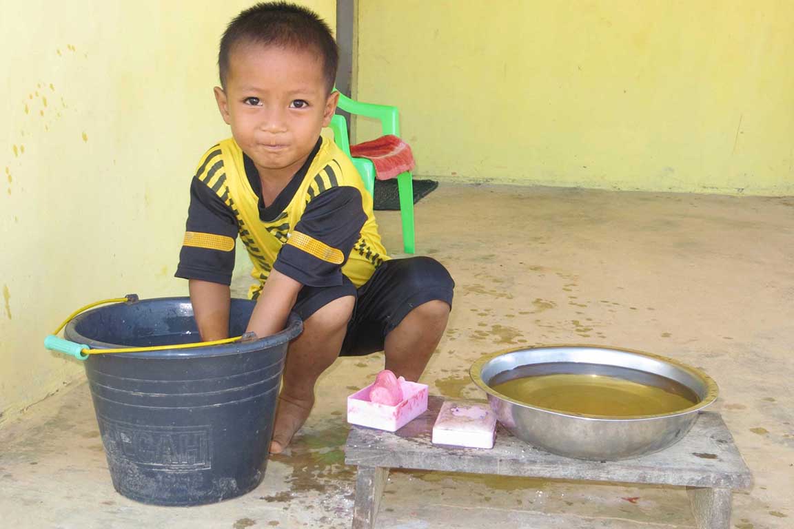Kind beim Abwasch auf Borneo